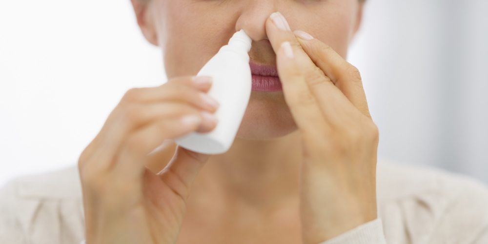 closeup on young woman using nose drops